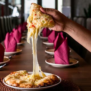 Melted cheese stretching from freshly baked cheese naan at Sakura Asian Dining & Bar