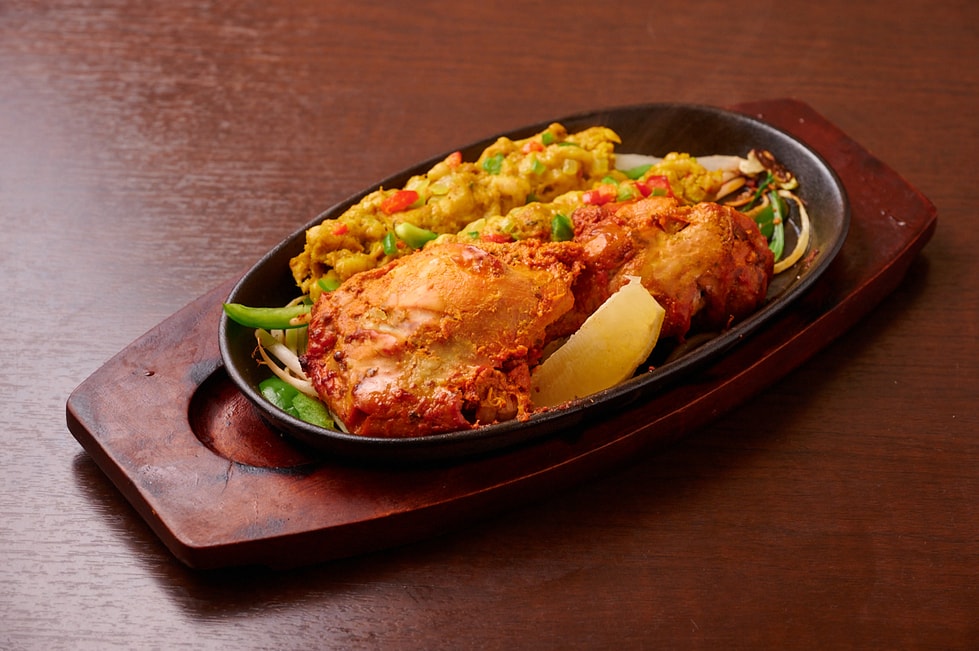 野菜と一緒に鉄板で提供するタンドリーチキン
